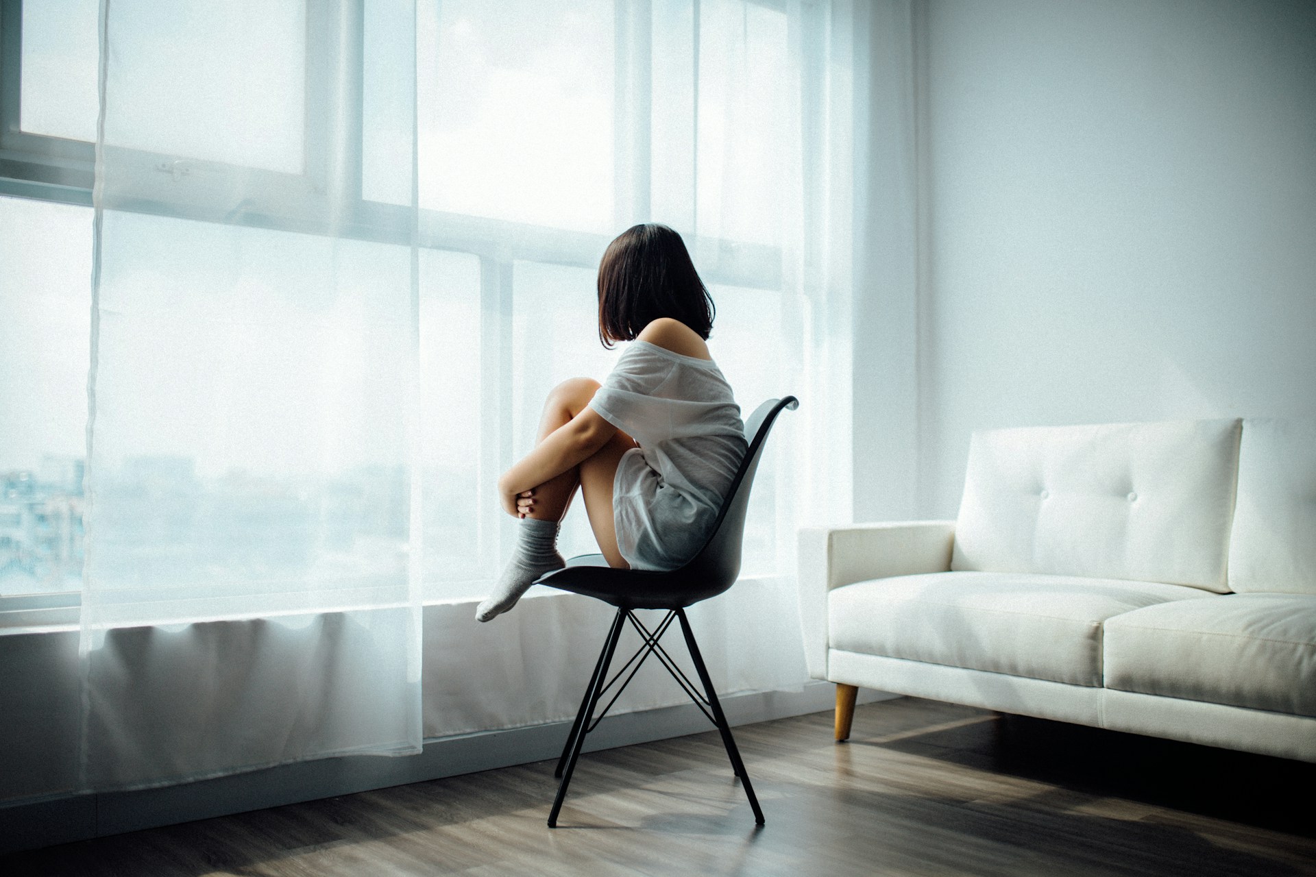 Mujer triste sentada de espalda frente a una ventana