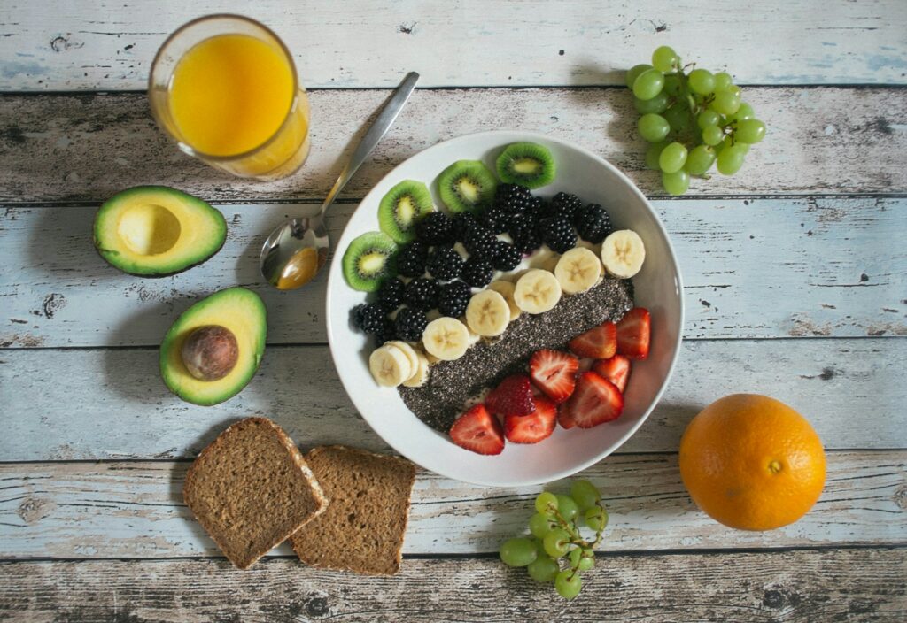 Bowl de alimentos que promueven la producción de serotonina con yogurt con frutas y semillas acompañado de aguacate y jugo de naranja