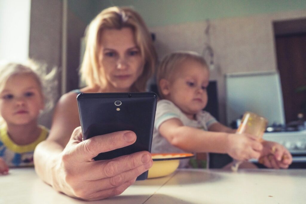 Mother texting whole holding two babies